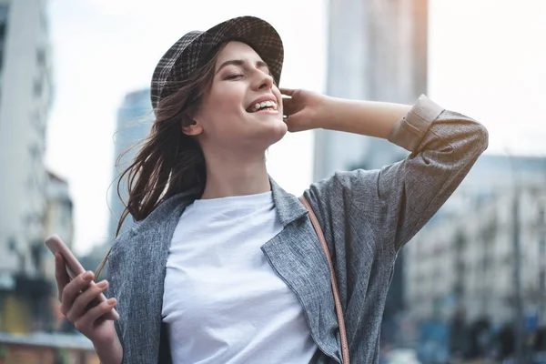 Allegro signora con smartphone sta sorridendo in strada — Foto Stock