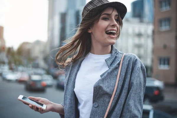 Mujer joven con teléfono se ríe en la calle — Foto de Stock