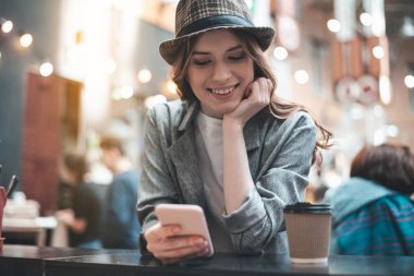 Sırıtan Bayan smartphone kafeteryasında sohbet