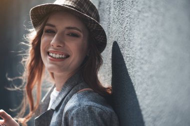 Gülümseyen genç bayan duvara yakın ayakta