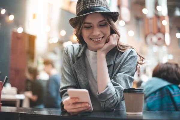 Sorridente signora è in chat su smartphone in caffetteria — Foto Stock