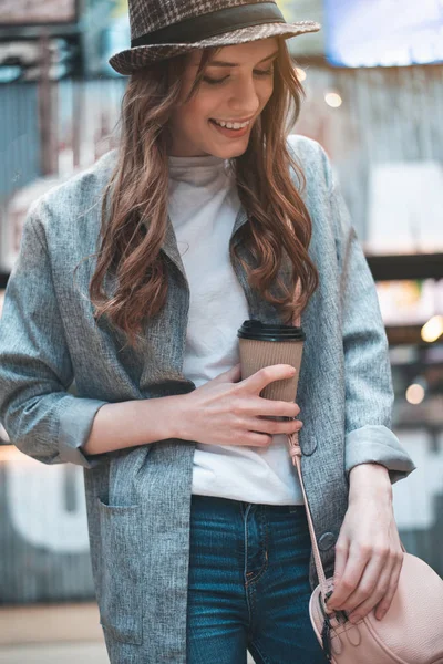 Улыбающаяся женщина с чашкой кофе на улице — стоковое фото