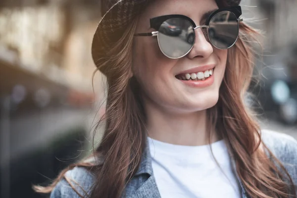 Jolie jeune femme sourit avec des lunettes de soleil — Photo