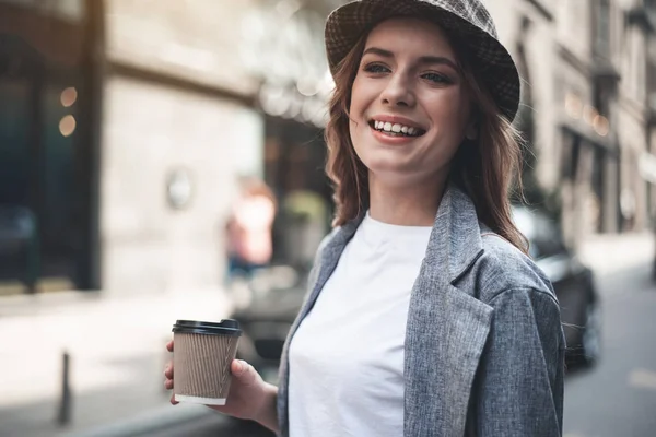 Jovencita sonriente con taza de café en la calle — Foto de Stock