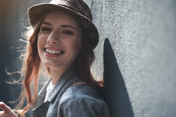 Jeune femme souriante debout près du mur — Photo