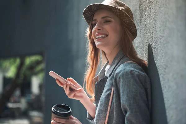 Menina sorridente com xícara de café e smartphone — Fotografia de Stock