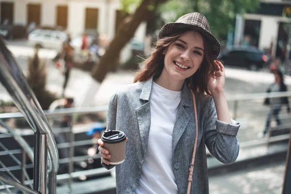 Young smiling lady standing outside with hot drink — Stock Photo, Image