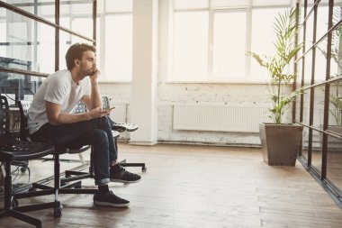 Düşünceli erkek elinde telefon tutmak