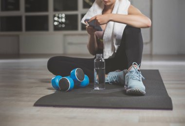 Spor salonunda telefonunu kullanarak ince kız