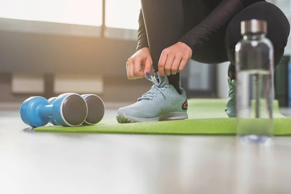 Woman tying shoelaces in gym