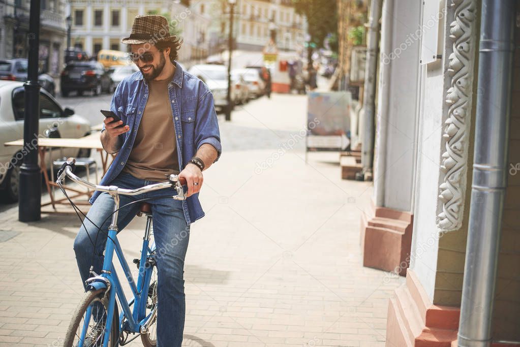 Enjoyed guy sitting on bike with device