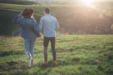 Sıcak yaz akşamları yeşil tepe üzerinde yürüme çift