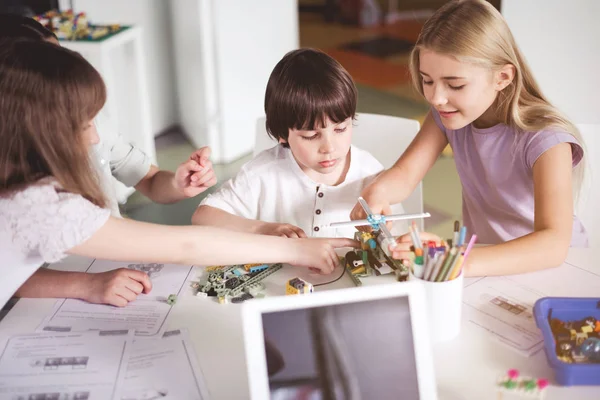 Chicas Felices Ayudando Niño Interesado Haciendo Constructor Forma Helicóptero Mientras —  Fotos de Stock