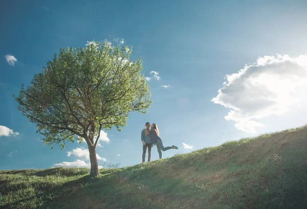 Speels meisje met jonge man door boom — Stockfoto