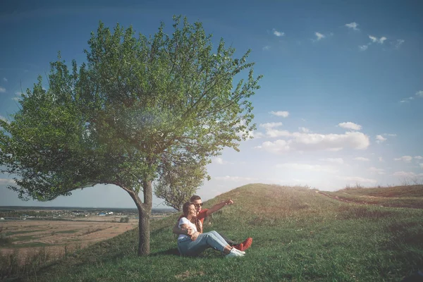 Chica joven y novio sentado junto al árbol —  Fotos de Stock