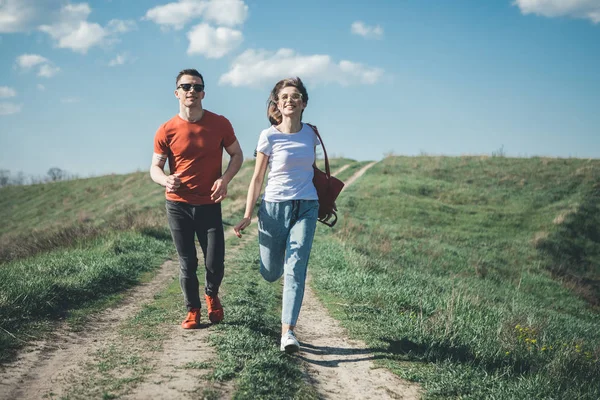 Улыбающиеся мужчина и женщина бегут по лугу — стоковое фото