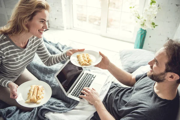 Cheerful girlfriend is bringing sweet morning meals to boyfriend — Stock Photo, Image