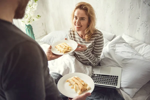 Glada damen tar emot välsmakande måltid i sängen från partner — Stockfoto