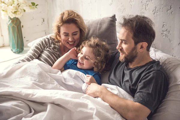 Beata famiglia sta iniziando il nuovo giorno insieme in dormitorio luminoso — Foto Stock