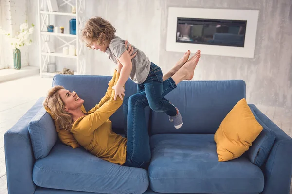 Riendo la madre y el niño se divierten en el sofá —  Fotos de Stock