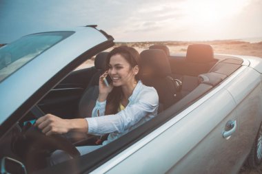 Smartphone taşıma içinde konuşan neşeli kadın sürücü 