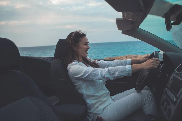 Happy young woman sitting at steering wheel of cabriolet — Stock Photo, Image