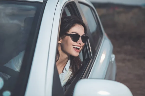 Chica alegre mirando el paisaje a través de la ventana del coche — Foto de Stock