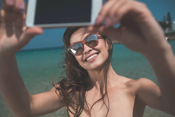 Une jeune femme positive prenant des photos au téléphone au bord de la mer — Photo