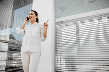 Verandada duran ve telefonla konuşan memnun işkadını düşük açılı. O tutan parmağını. Kopya alanı sağ tarafında