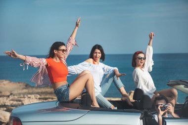 Neşeli genç insanlar sahil boyunca arabada seyahat