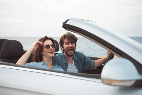 Alegre jovem casal no amor está sentado no carro — Fotografia de Stock