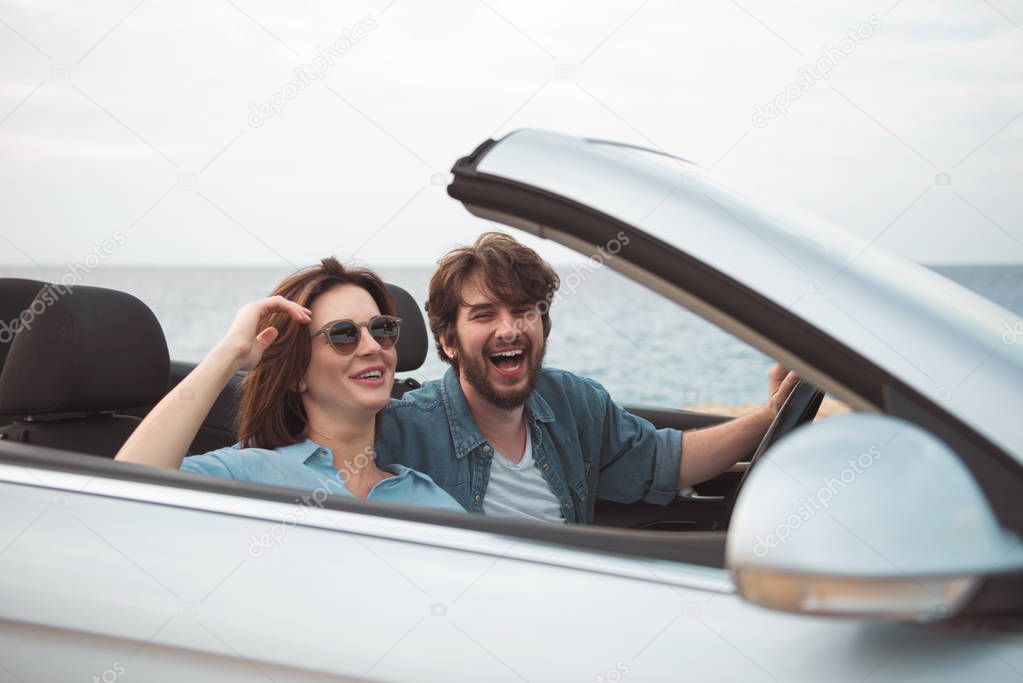 Cheerful young couple in love is sitting in car
