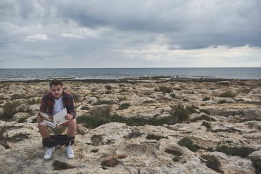 Lavabo üzerinde dergi okuma ciddi genç adam 