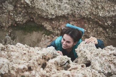 Heyecanlı genç kadın üzerinde kayalık dağ tırmanma 