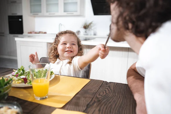 Happy girl feeding her father by fresh salad with joy — Stock Photo, Image