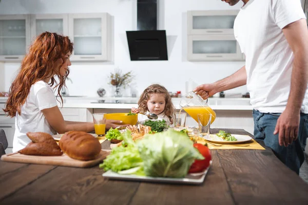 Cheerful family eating in kitchen together — Stock Photo, Image