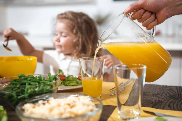 Pai derramando suco de laranja em vidro para a menina — Fotografia de Stock