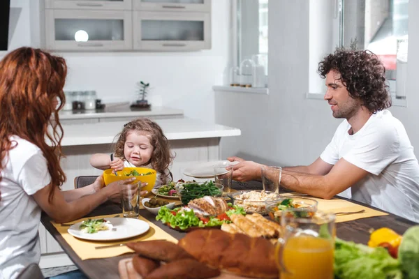 Счастливые отец и мать кормят своего ребенка здоровой пищей — стоковое фото