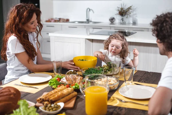 Joyful parents and girl dining together in kitchen — Stock Photo, Image