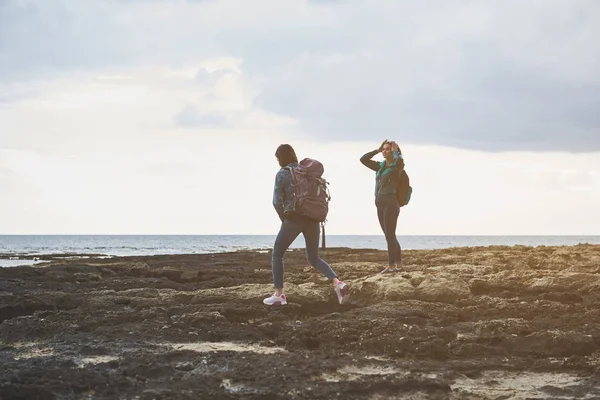Gelukkig vrouwelijke toeristen wandelen op rotsachtige kust — Stockfoto