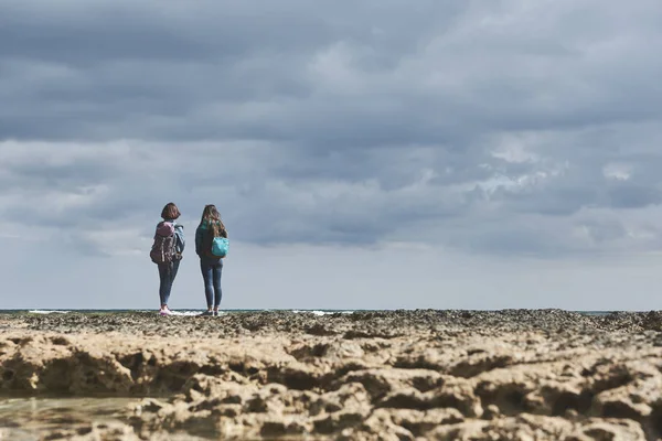 Rustige meisjes ontspannen op rotsachtige kust — Stockfoto