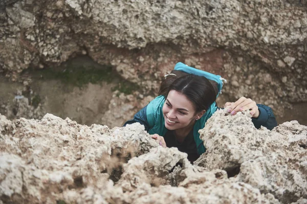 Heyecanlı genç kadın üzerinde kayalık dağ tırmanma 