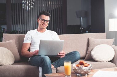 Evde bilgisayar üzerinde çalışma neşeli genç adam 