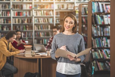 Cheerful woman studying in library clipart