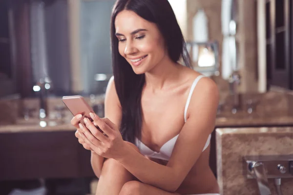 Usmívající se žena pomocí smartphone v koupelně — Stock fotografie