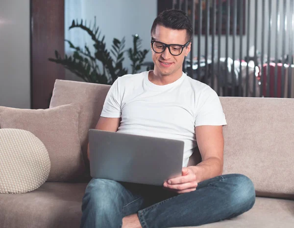 Oturma odasında dizüstü bilgisayarda yazarak memnun erkek serbest meslek 