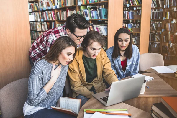 Los estudiantes asombrados viendo en el ordenador portátil — Foto de Stock