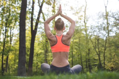 Sportif Bayan yeşil çim üzerinde yoga uygulamak