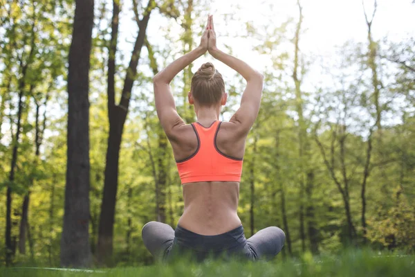 Sportif Bayan yeşil çim üzerinde yoga uygulamak