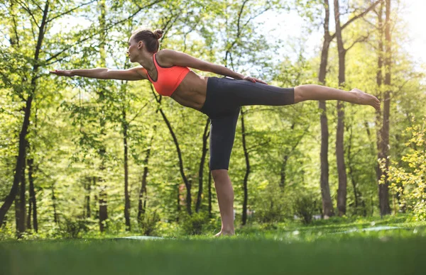 Sportif kadın asana yeşil parkta duruyor